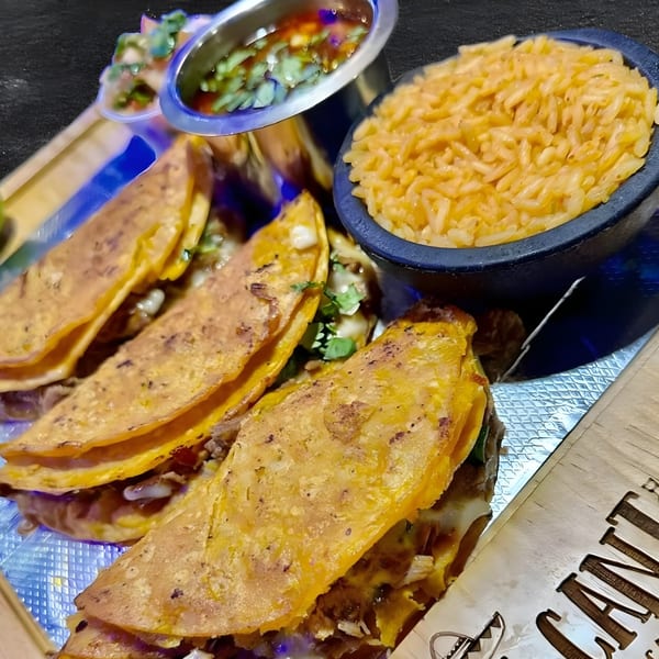La Cantina Mexican Restaurant's birria tacos with rice and a side of consommé on a wooden tray.